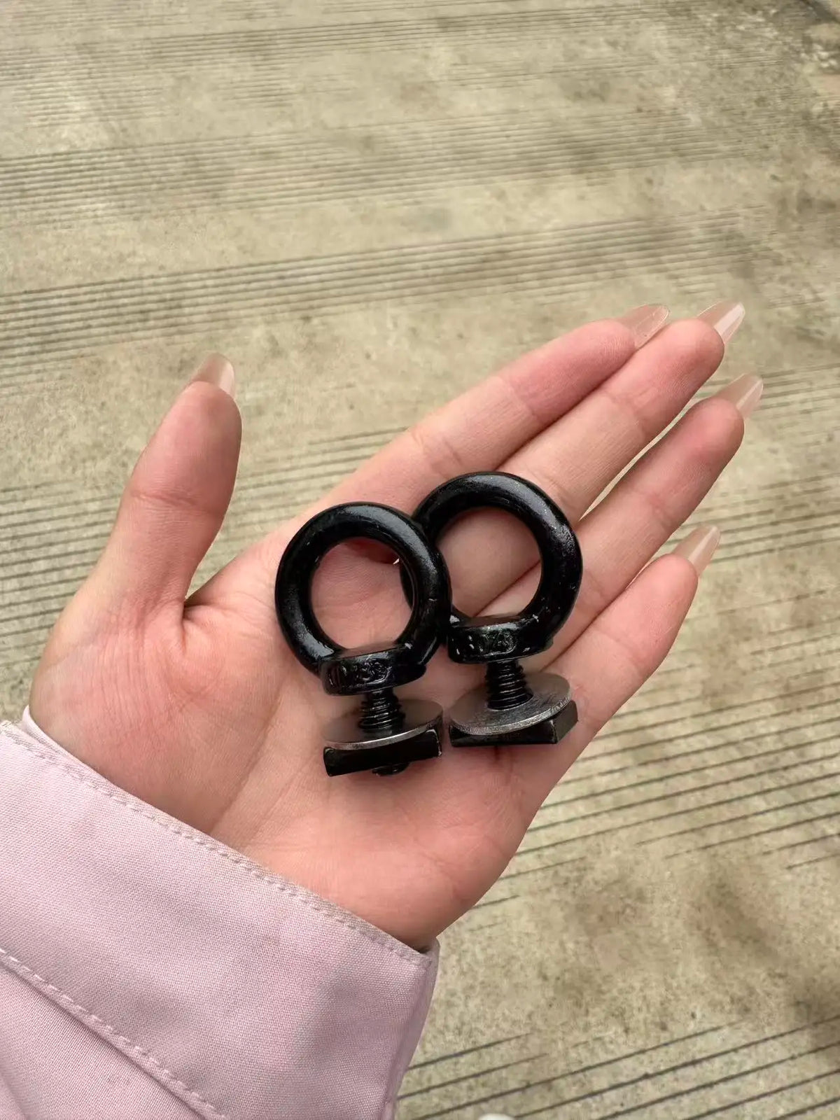 Black M8 eye bolts held in hand for scale